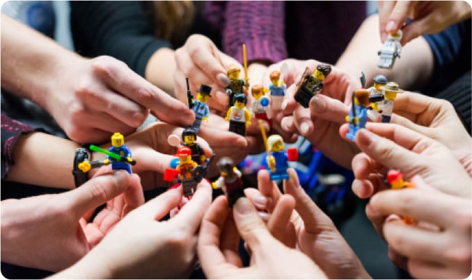 Hands holding up mini lego figurines